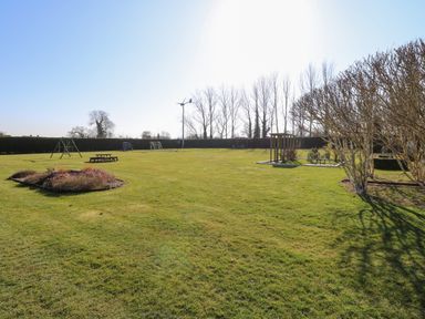 A large grassy garden with swings picnic table soccer goal and trees at Swallow Barn Holton near Halesworth