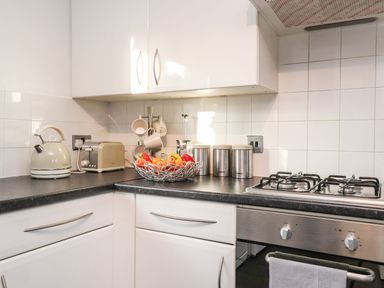 A kitchen corner with a kettle toaster fruit bowl canisters and a gas stove at Arnside House in South Lakeland Leisure Village