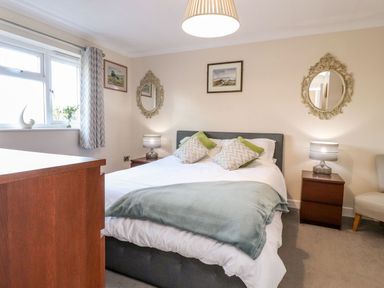 A bedroom with a bed bedside tables lamps mirrors and a chest of drawers at Arnside House in South Lakeland Leisure Village