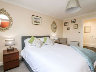 A bedroom with a bed pillows bedside tables lamps mirrors and framed pictures at Arnside House in South Lakeland Leisure Village