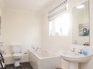 A bathroom with a toilet bathtub and sink next to a window at Arnside House in South Lakeland Leisure Village