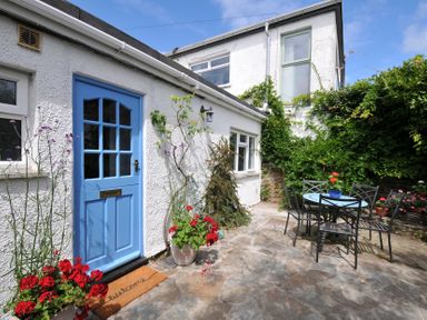 A garden with a blue door and a table with chairs at 2 Porthilly Cottages Rock