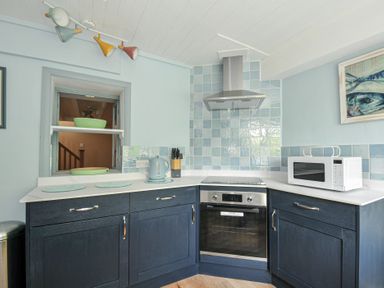 A kitchen with blue tiles and appliances at 2 Porthilly Cottages in Rock