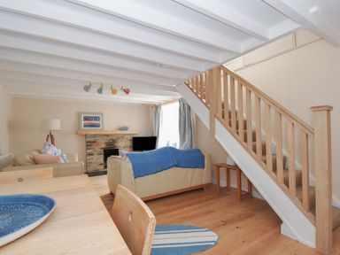 A living room with a sofa and dining table at 2 Porthilly Cottages Rock