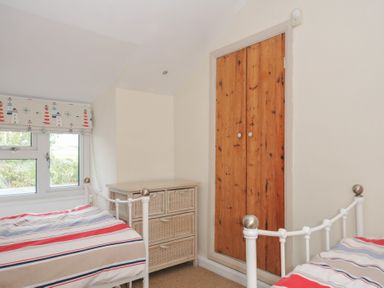 A bedroom with two beds and a dresser at 2 Porthilly Cottages Rock