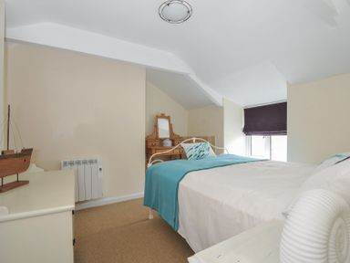 A bedroom with a bed and table at 2 Porthilly Cottages in Rock