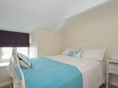 A bedroom with a bed, pillow, and window at 2 Porthilly Cottages in Rock