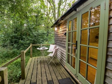 An outdoor patio with a table and chairs at Woodlands Retreat Shepherd's Hut Brundish near Laxfield