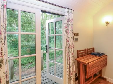 A room with a table and chairs leading to an outdoor area at Woodlands Retreat Shepherd's Hut Brundish near Laxfield