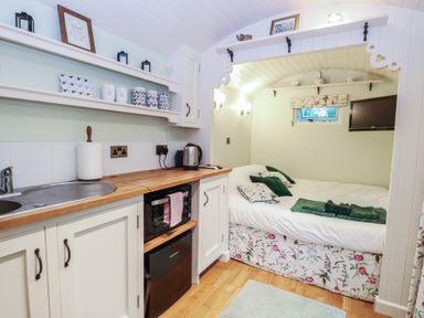 A bedroom with a kitchenette and bed at Woodlands Retreat Shepherd's Hut in Brundish near Laxfield