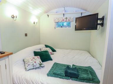 A bedroom with a bed and television at Woodlands Retreat Shepherd's Hut in Brundish near Laxfield