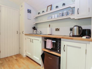 A kitchen with cabinets and appliances at Woodlands Retreat Shepherd's Hut, Brundish near Laxfield
