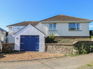 A detached house with a tiled roof and blue garage doors at Arfryn in Solva