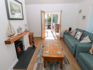 A living room with a fireplace a wooden coffee table and a sofa with cushions at Arfryn in Solva