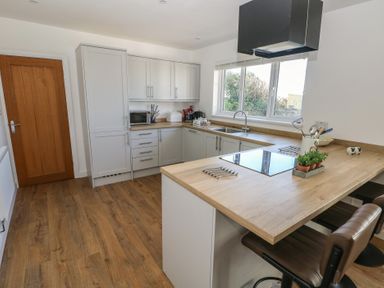 A kitchen with wooden countertops and flooring and white cabinets at Arfryn in Solva