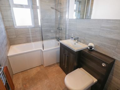 A bathroom with a bathtub shower combination sink vanity toilet and towel radiator at Arfryn in Solva