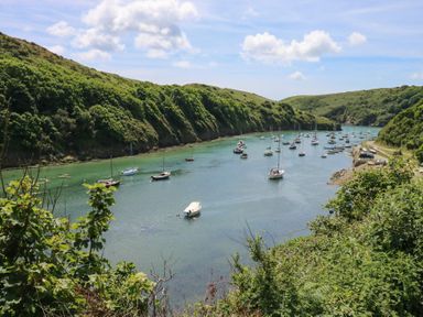 A river with boats anchored between green hills at Arfryn in Solva