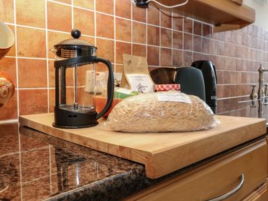 A kitchen countertop with a bread loaf plastic bag a French press coffee maker and other kitchen items at Dromore Cottage in Norham