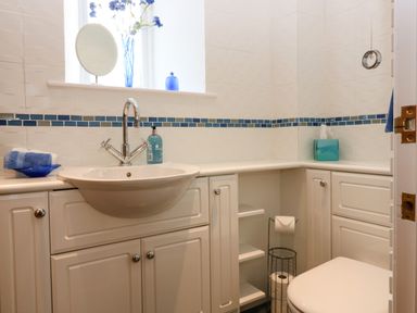 A bathroom with a sink toilet towel and tissue box at Dromore Cottage in Norham