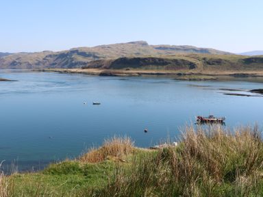 A body of water with two boats and hills in the background at WildLuing Cullipool Isle Of Luing