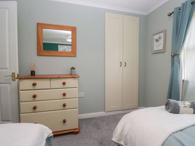 A bedroom with a chest of drawers mirror wardrobe and beds with folded towels at Sunset Retreat in South Lakeland Leisure Village near Carnforth