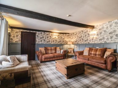 A living room with two brown sofas a wooden chest coffee table and plaid carpet at Dragon House in Bilbrook near Minehead