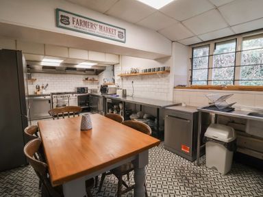 A kitchen with a wooden table and chairs stainless steel counters and appliances at Dragon House in Bilbrook near Minehead