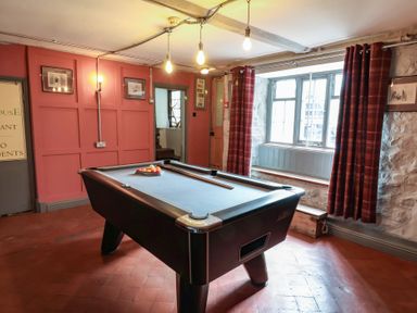 A games room with a pool table and red curtains by a window at Dragon House in Bilbrook near Minehead