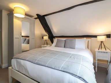 A bedroom with a bed grey blanket pillows two bedside tables lamps and a wardrobe with mirror at Dragon House in Bilbrook near Minehead