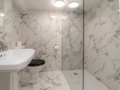 A bathroom with a sink toilet and a walk in shower with marble tiled walls and floor at Dragon House in Bilbrook near Minehead