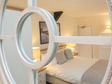 A bedroom with a bed two pillows bedside tables lamps a framed picture and a door at Dragon House Bilbrook near Minehead