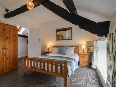A bedroom with a wooden bed and nightstands with lamps and a wardrobe at Dragon House in Bilbrook near Minehead