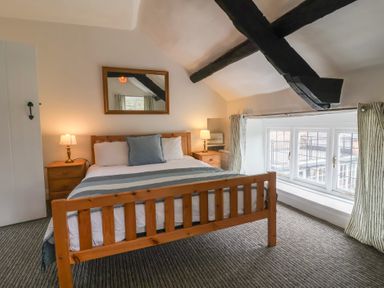 A bedroom with a wooden bed and two bedside tables with lamps at Dragon House in Bilbrook near Minehead