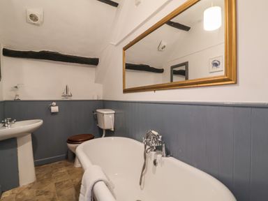 A bathroom with a bathtub a toilet and a sink with a large mirror above at Dragon House in Bilbrook near Minehead