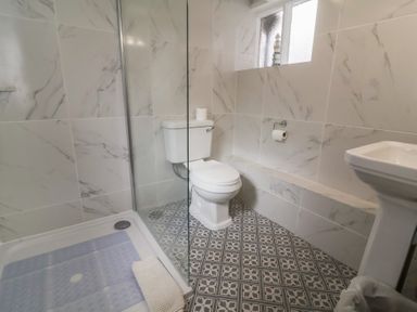 A bathroom with a toilet shower area and a pedestal sink at Dragon House in Bilbrook near Minehead