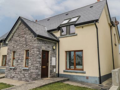 A stone and plaster exterior house with a dark wooden door and windows at C65 Cahermore Holiday Village in Enniscrone County Sligo