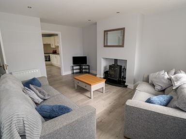 A living room with two grey sofas a wooden coffee table a small TV and a wood stove at C65 Cahermore Holiday Village in Enniscrone County Sligo