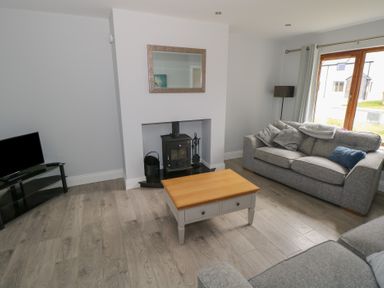 A living room with two grey sofas a wooden coffee table a fireplace and a television at C65 Cahermore Holiday Village in Enniscrone County Sligo
