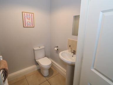 A bathroom with a toilet sink mirror towel on a radiator and framed picture on the wall at C65 Cahermore Holiday Village in Enniscrone County Sligo