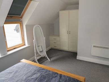 A bedroom with a bed, a standing mirror, a wardrobe with drawers, and a window at C65 Cahermore Holiday Village in Enniscrone County Sligo