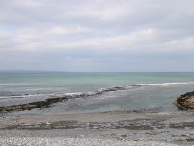 A rocky beach with calm sea and cloudy sky at C65 Cahermore Holiday Village in Enniscrone County Sligo
