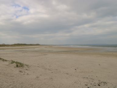 A sandy beach with patches of grass and a cloudy sky at C65 Cahermore Holiday Village in Enniscrone County Sligo