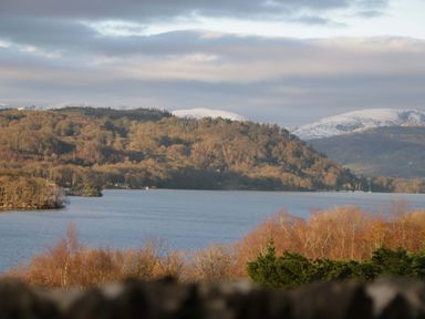 A view of a lake with surrounding mountains and trees at Marina View in Bowness-On-Windermere
