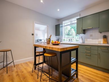 A kitchen with an island bar and stools at Marina View in Bowness-On-Windermere
