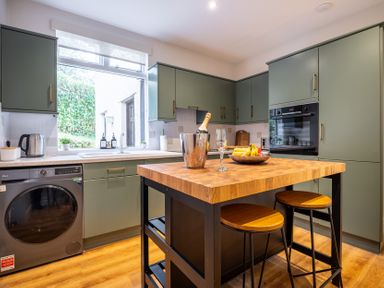A kitchen with a wooden table and bar stools at Marina View in Bowness-On-Windermere