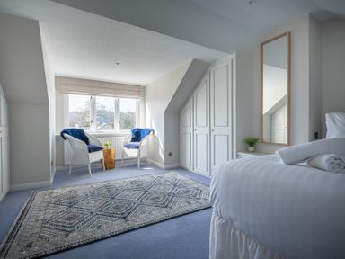 A bedroom with a bed, two chairs, and a window at Marina View in Bowness-On-Windermere