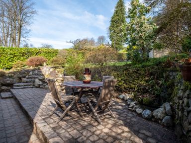 A garden with a table and chairs at Marina View in Bowness-On-Windermere