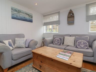 A sitting room with grey sofas and cushions and a wooden coffee table at Gatekeeper's Cottage in Bilbrook near Minehead