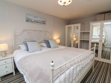 A bedroom with a white metal bed frame striped carpet and a wardrobe with mirrored doors at Gatekeeper's Cottage Bilbrook near Minehead