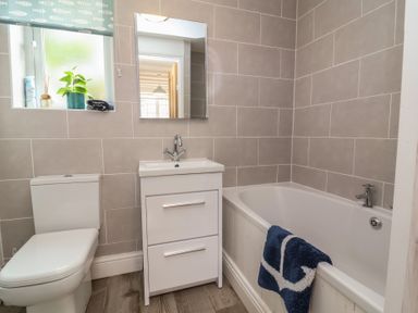 A bathroom with a toilet sink with cabinet bathtub and window at Gatekeeper's Cottage Bilbrook near Minehead